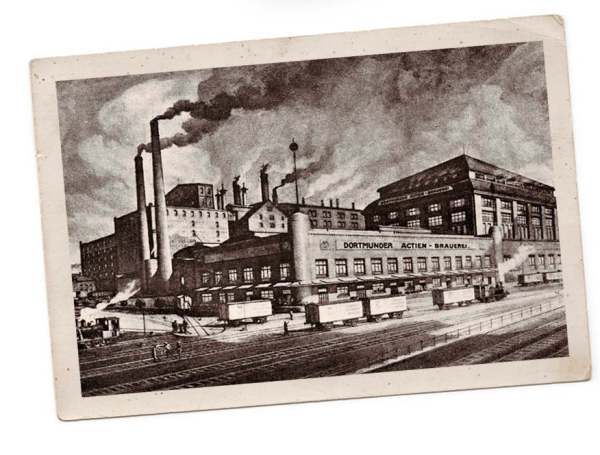 Historische schwarz-weiß Aufnahme einer großen industriellen Brauerei mit rauchenden Schornsteinen.