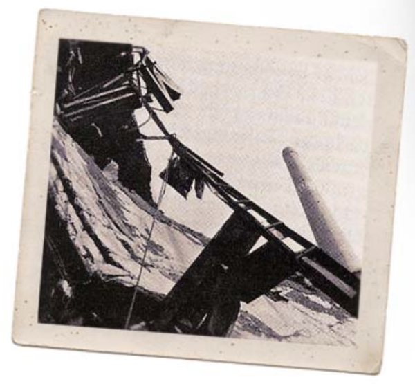 Beschädigte Holzkonstruktion auf einer schneebedeckten Berghang in Schwarz-Weiß.