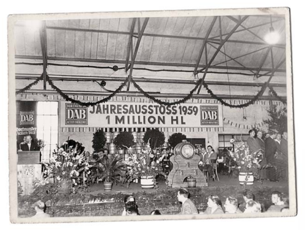 Eine historische Schwarz-Weiß-Fotografie zeigt eine Versammlung in einer dekorierten Halle zur Feier eines Brauerei-Jahresabschlusses 1959.