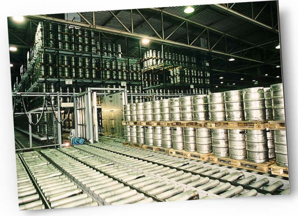 Ein großes Lager mit vielen Metallfässern und Flaschenregalen. Rollbahnen transportieren die Güter.